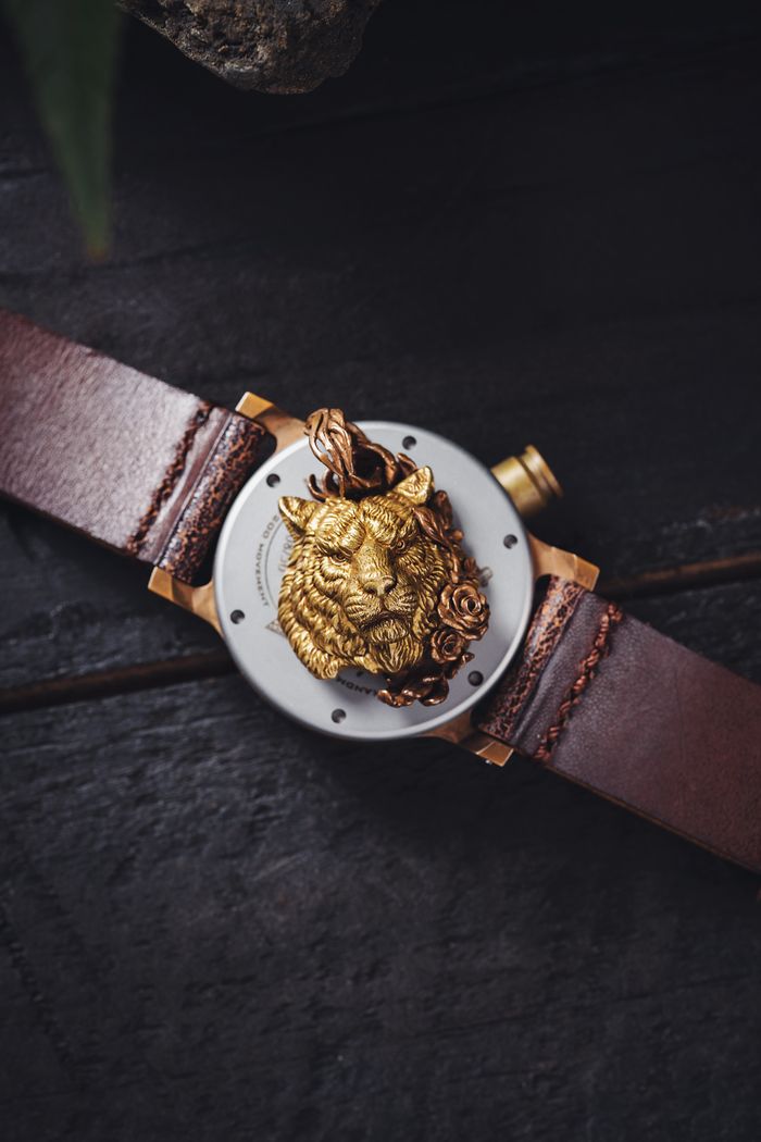 Home Close-up of a stylish wristwatch featuring a detailed golden lion head pendant.