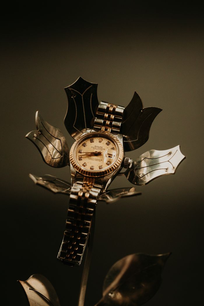 Home Gold watch artfully displayed on metallic flower, creating a luxurious and unique composition.